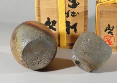 Ein tokkuri und ein guinomi von Fujiwara Kei. Hier die Signatur des Künstlers auf beiden Gefäßen. Im Hintergrund die Holzdosen.