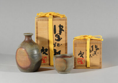 Ein tokkuri und ein guinomi von Fujiwara Kei. Im Hintergrund die beschrifteten Holzdosen.