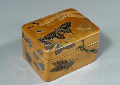 Eine goldene Lackdose, dekoriert mit großen Insekten.