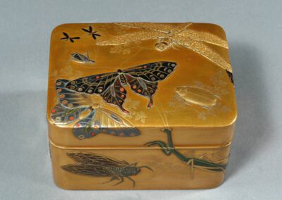 Eine goldene Lackdose, dekoriert mit großen Insekten.