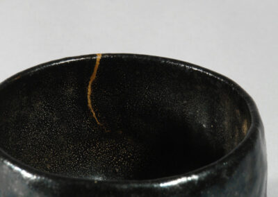 Eine schwarze Teeschale aus Raku-Keramik von Kichizaemon IX. Hier ein Detail mit der feinen Goldlackreparatur kintsugi.
