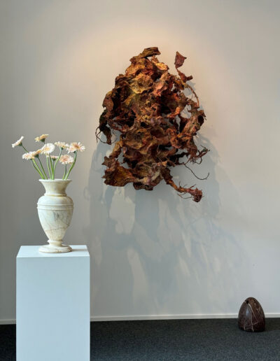 Eine klassizistische Vase aus Marmor. Hier mit Blumen in der Galerie fotografiert. Rechts eine Wandskulptur von Bernard Schultze. Unten rechts ein baktrischer Ritualstein.