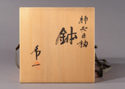 Eine große rote Schale hachi aus kaki-yu-Keramik des Künstlers Shimizu Uichi. Hier der Dosendeckel mit der Beschriftung des Künstlers.
